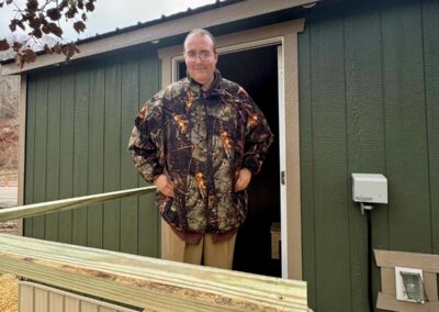 A gentleman smiles as he stands outside the door of his recently delivered tiny home